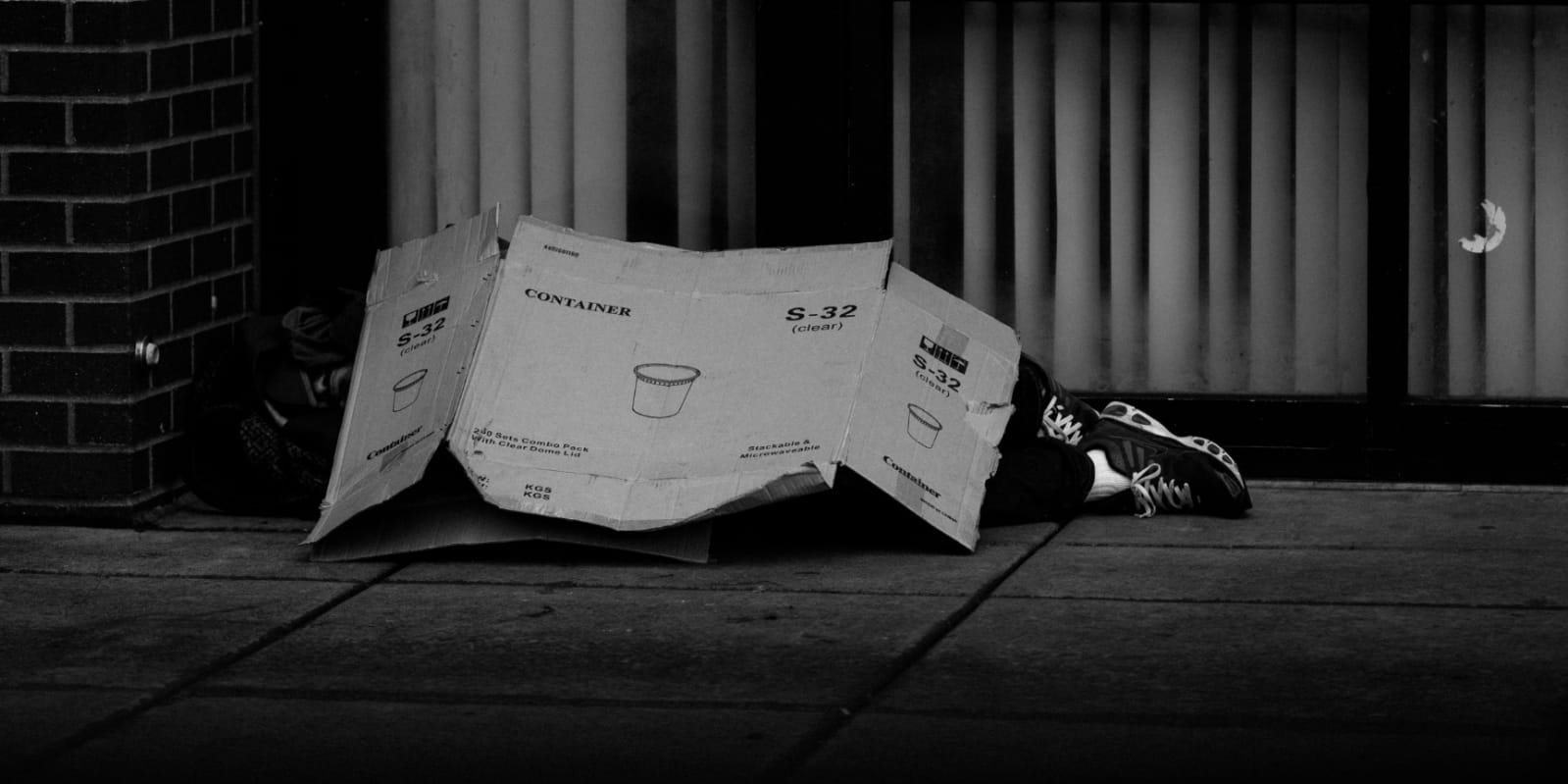 Pessoa em situação de rua coberto por papelão